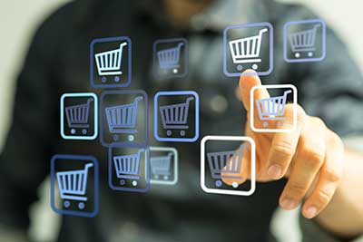Grupo Albatros Mano humana tocando una pantalla digital con carros de compra