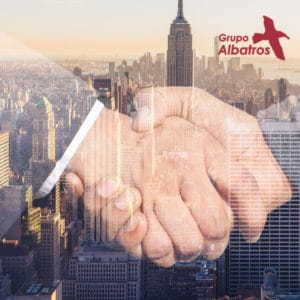 Grupo Albatros, apretón de manos de baja opacidad frente a la imagen de una ciudad de rascacielos al fondo