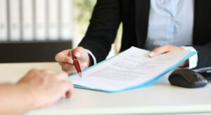 Grupo Albatros. Contrato laboral sostenido por un mano femenina que lo extiende hacia otra persona.